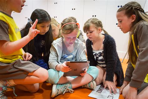 Four girls in Brownie uniform sat around a fifth girl holding an iPad